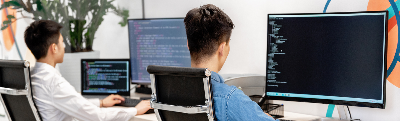 Two people pointing at a document on a table, one holding a pen