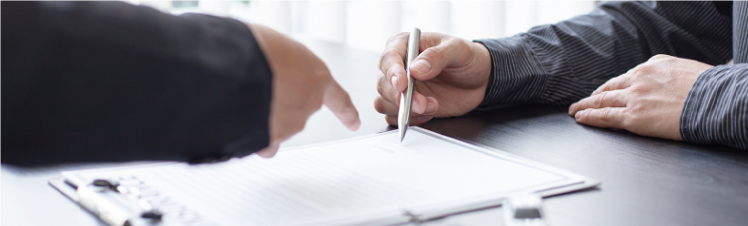 Two people pointing at a document on a table, one holding a pen