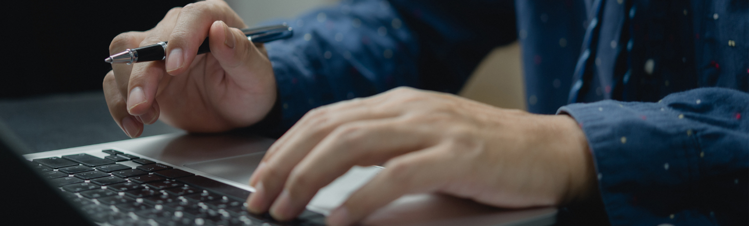 Two people pointing at a document on a table, one holding a pen